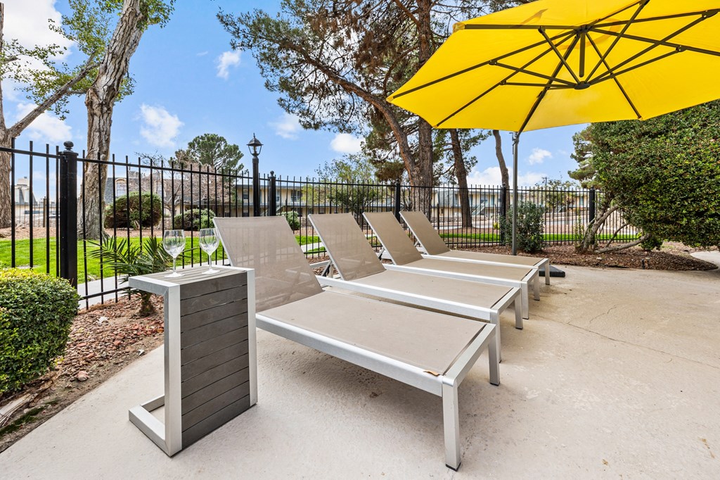 a row of lounge chairs with umbrellas in a park