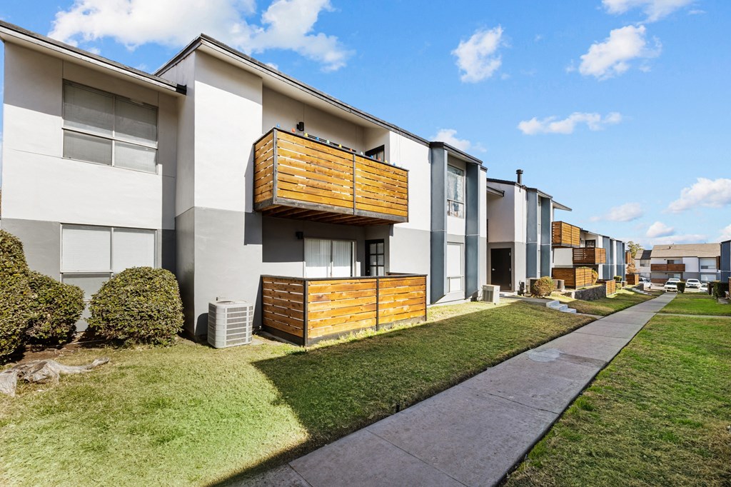 a row of townhomes with a sidewalk and grass