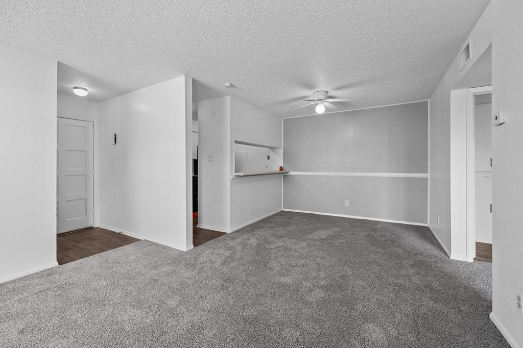 an empty living room with white walls and a ceiling fan