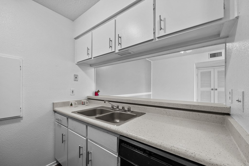 the kitchen of our studio apartment atrium with white cabinets and a sink