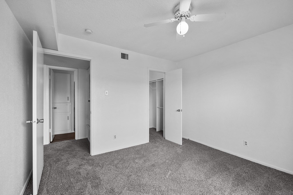 an empty living room with white walls and a ceiling fan