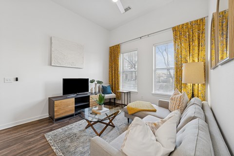 A living room with a grey couch, a wooden coffee table, and a painting on the wall.