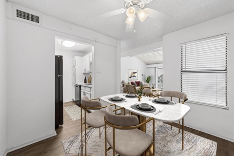 A dining room with a white table and chairs.