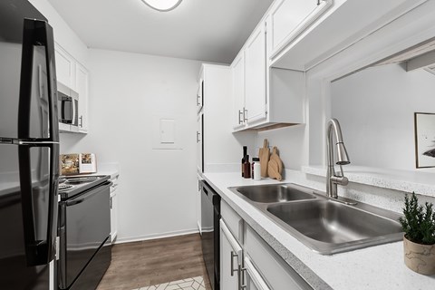 A modern kitchen with a black refrigerator and stainless steel sink.