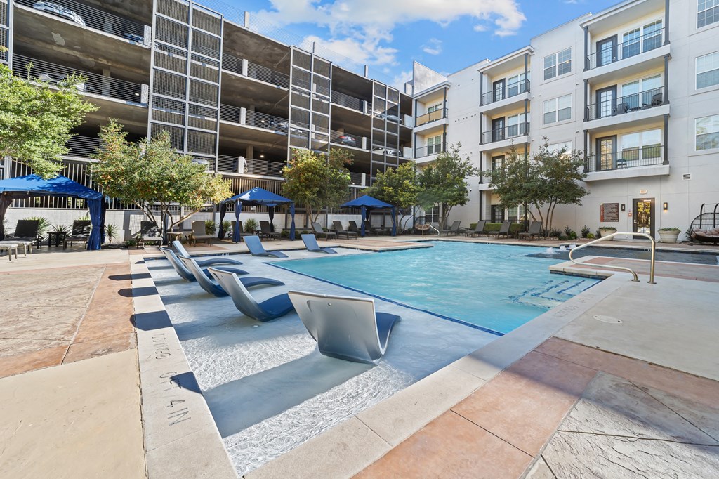 an apartment pool with lounge chairs in front of an apartment building