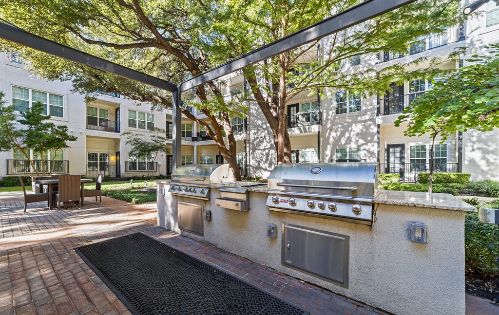 an outdoor kitchen with stainless steel appliances in front of an apartment building