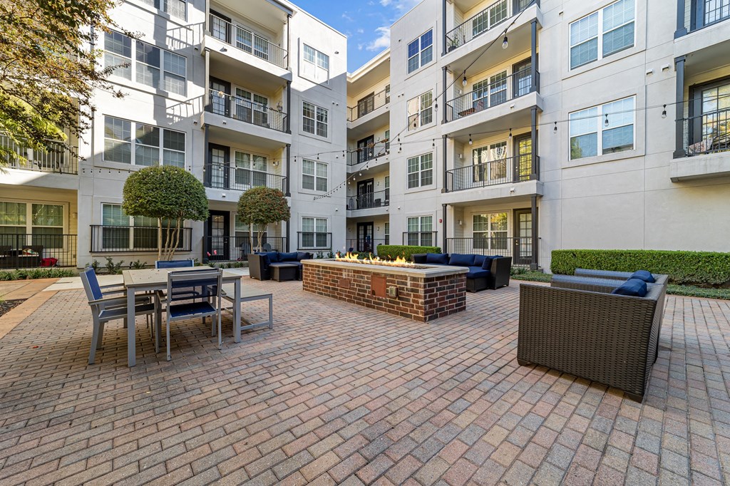 a brick patio with a fire pit in front of an apartment building