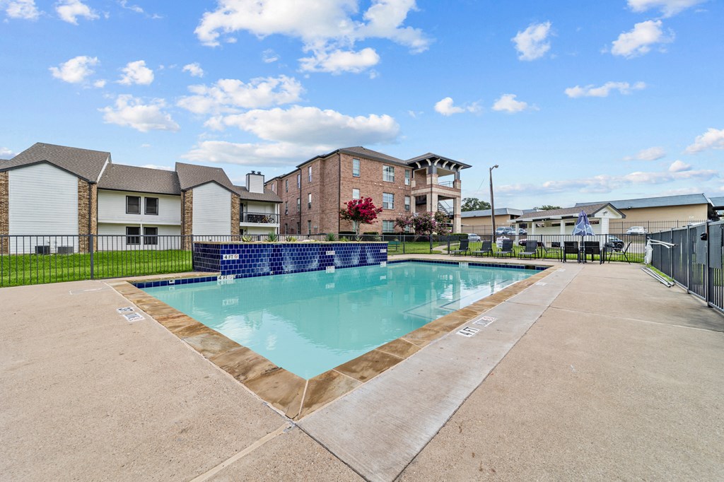 A swimming pool surrounded by a concrete floor and a fence.