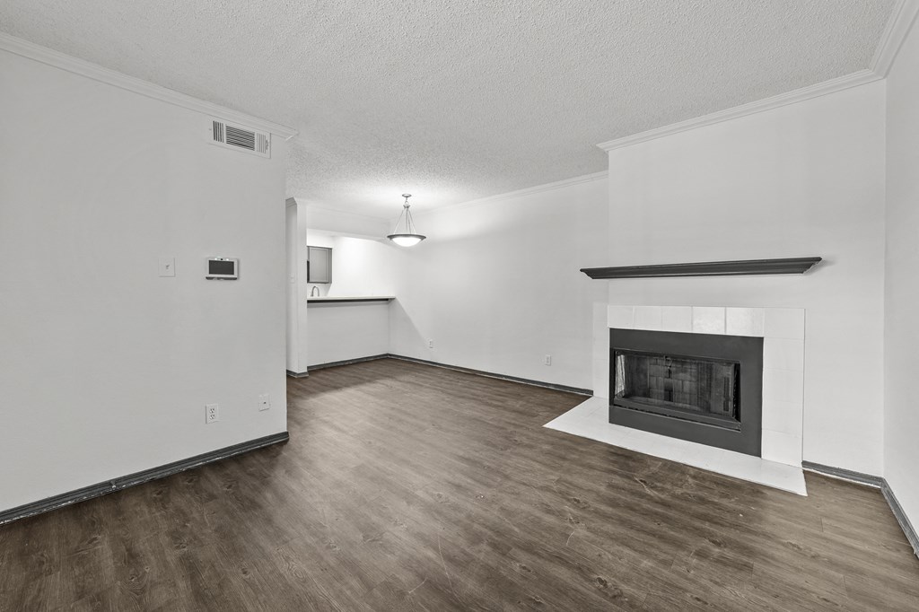 A large, empty room with a fireplace and wood flooring.