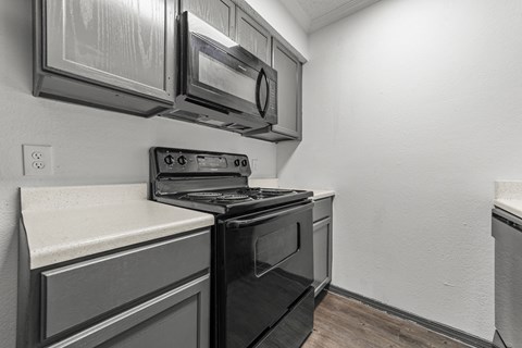 A black oven sits in a kitchen with a microwave and stove.