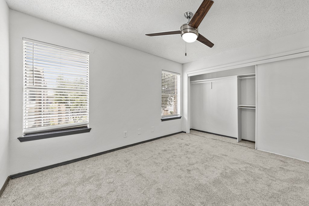 A room with a ceiling fan and a window with blinds.