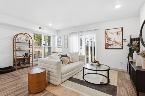 A living room with a white couch, a round coffee table, and a wooden side table.