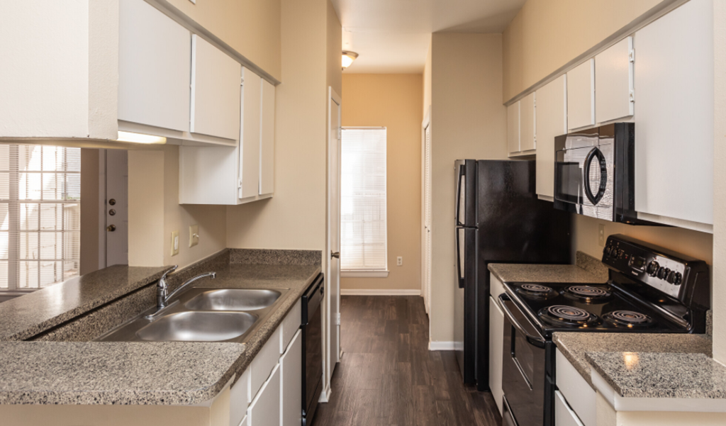 a kitchen with white cabinets and black appliances