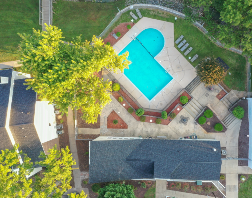 a birds eye view of a swimming pool in a garden with trees