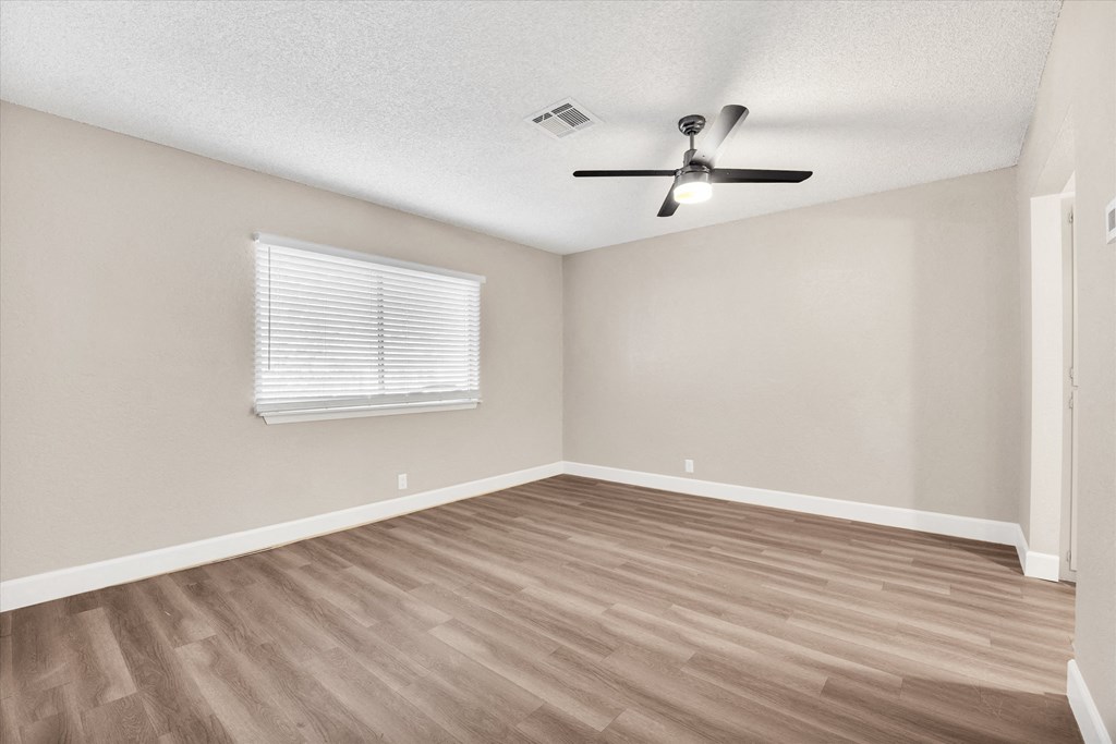 an empty bedroom with a ceiling fan and a window