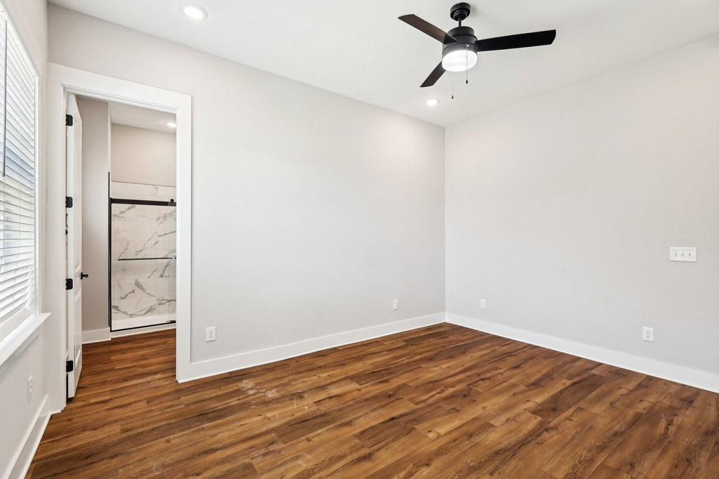 A room with a ceiling fan and wooden flooring.