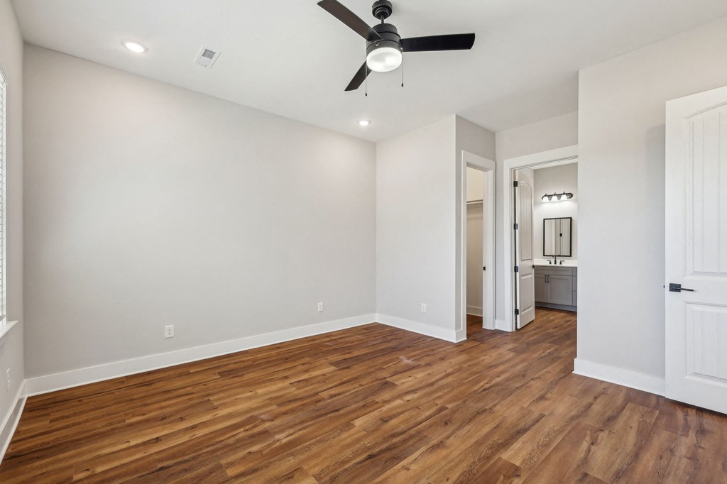 A room with a ceiling fan and wooden floors.