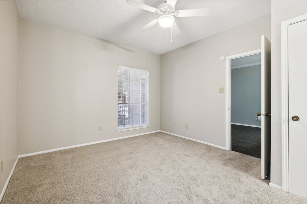 A room with a ceiling fan and carpeted floor.