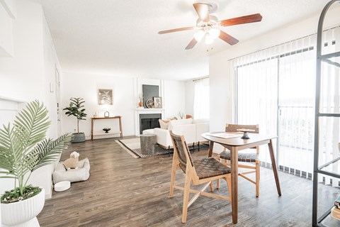 a living room with a ceiling fan and a table and chairs