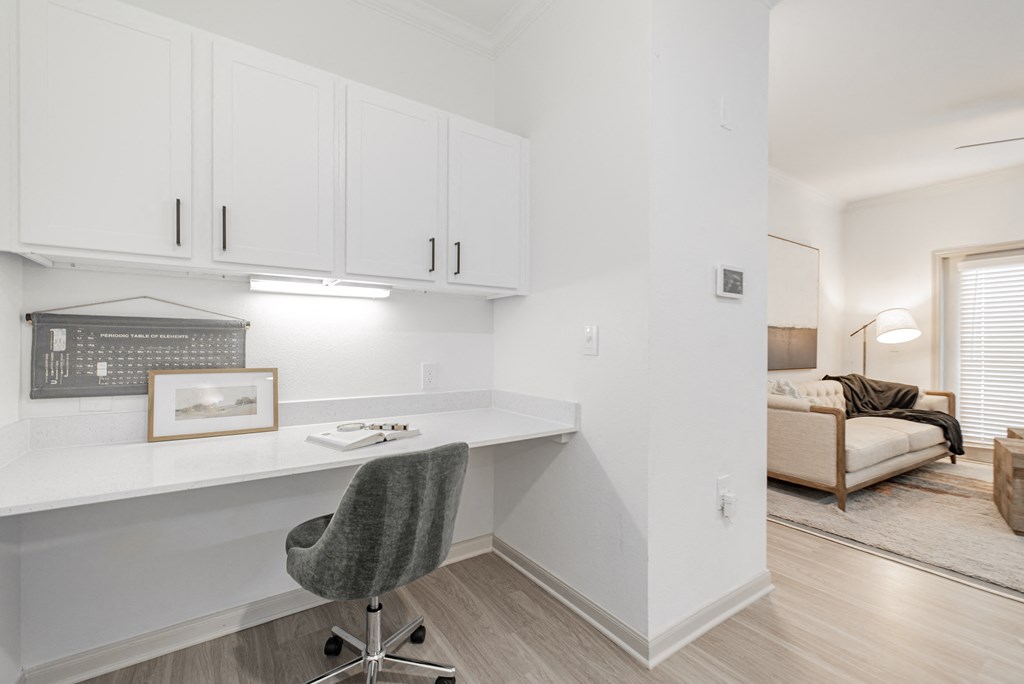 a home office with white cabinets and a desk with a chair
