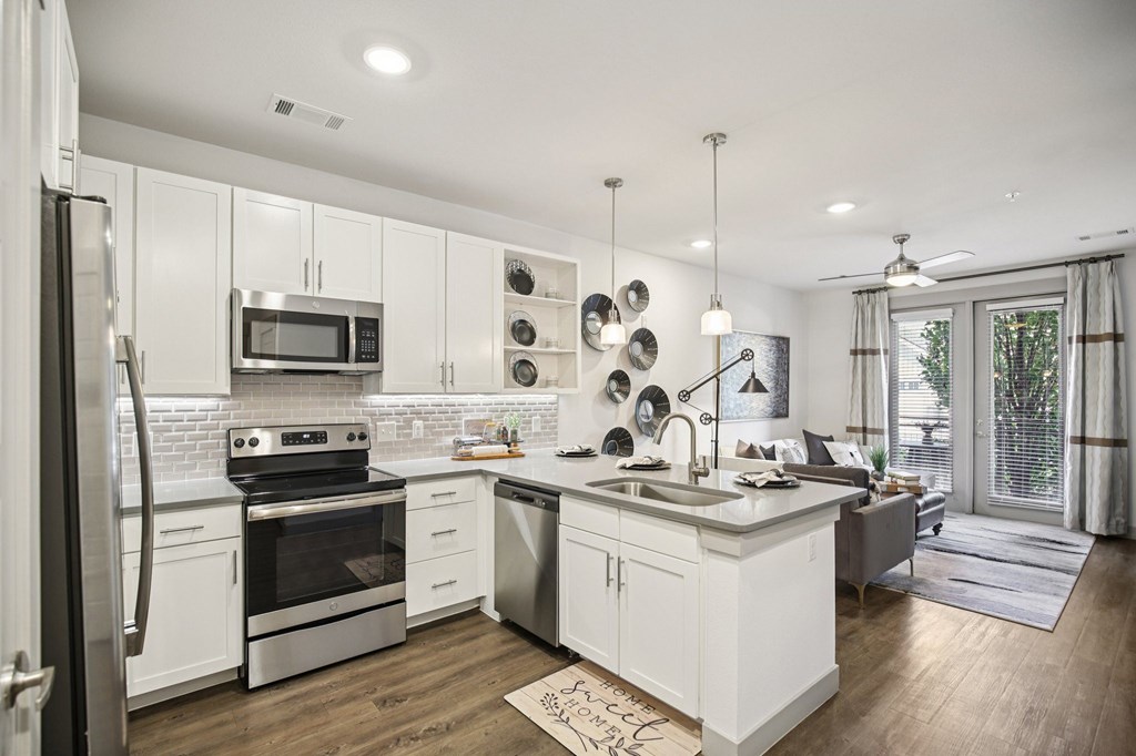A modern kitchen with white cabinets and stainless steel appliances.