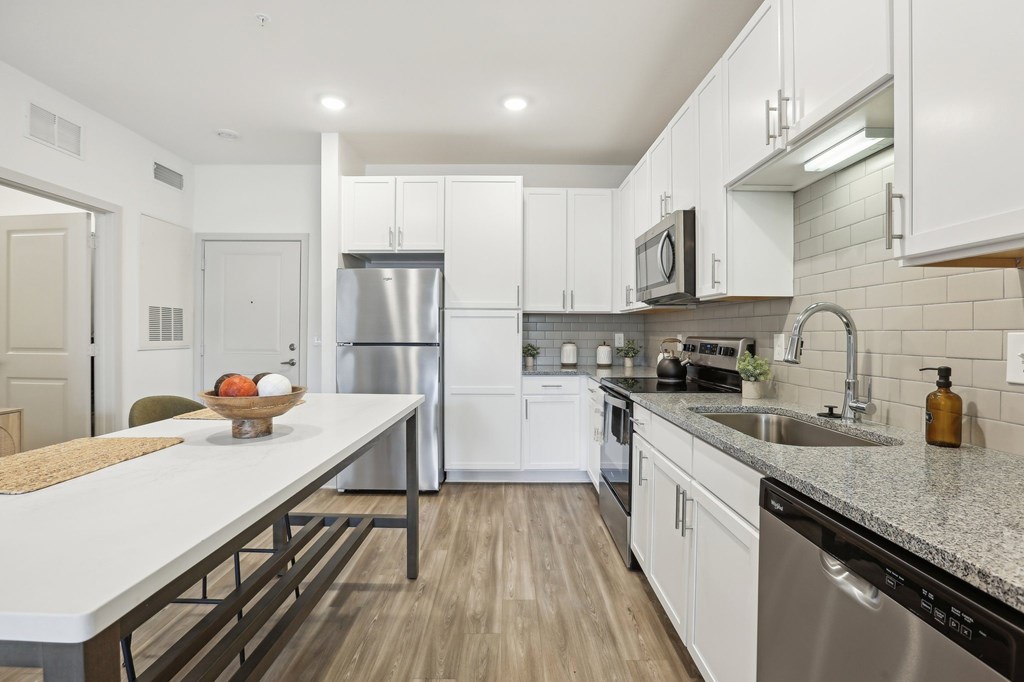 A kitchen with white cabinets and a wooden table.