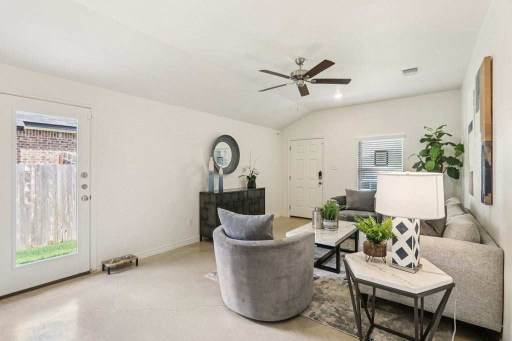 A living room with a grey couch, a grey armchair, a white coffee table, and a ceiling fan.