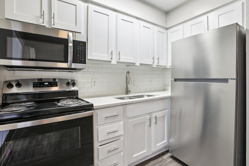 A modern kitchen with white cabinets and stainless steel appliances.