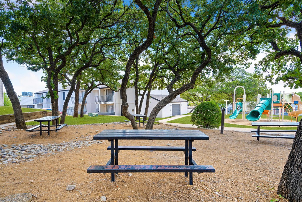 a picnic table in a park with a playground in the background