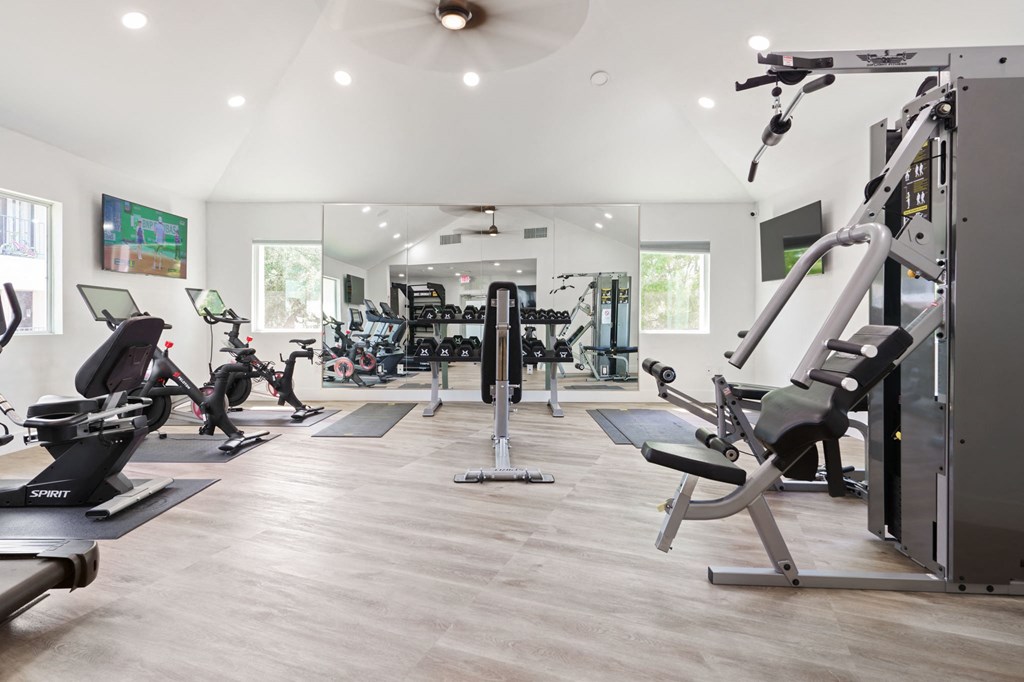 a gym with cardio equipment and weights on a wooden floor