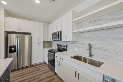 A modern kitchen with white cabinets and a stainless steel refrigerator.