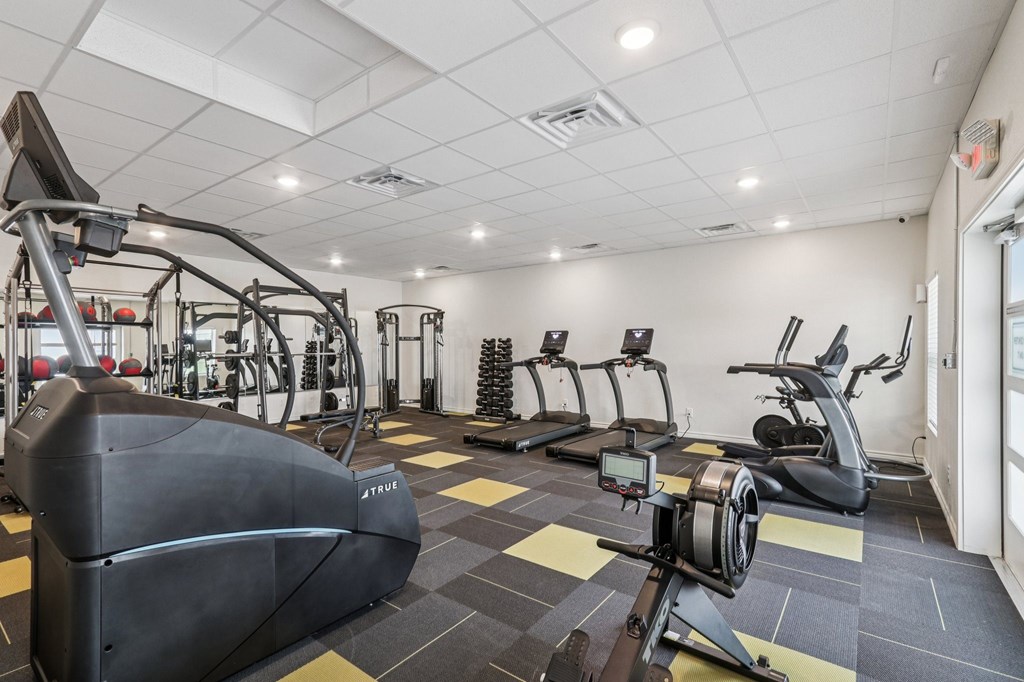 A gym with a variety of exercise equipment including treadmills, stationary bikes, and elliptical machines.