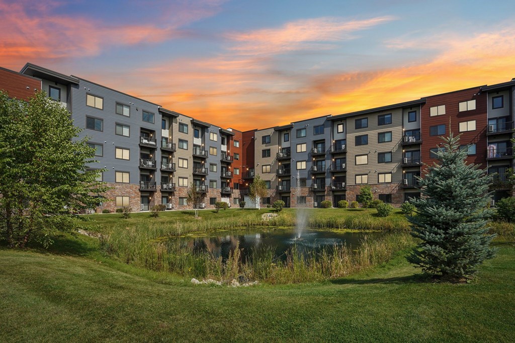 A row of apartment buildings with a pond in the foreground.