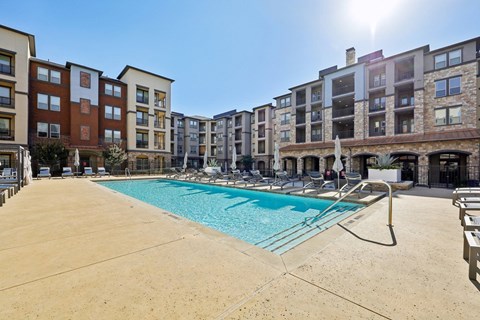 A sunny day at a pool in front of apartment buildings.
