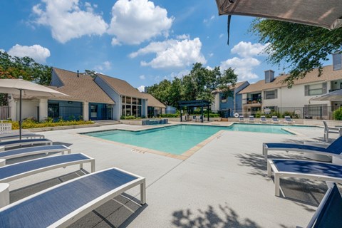 A sunny day at the pool with lounge chairs and a clear blue sky.