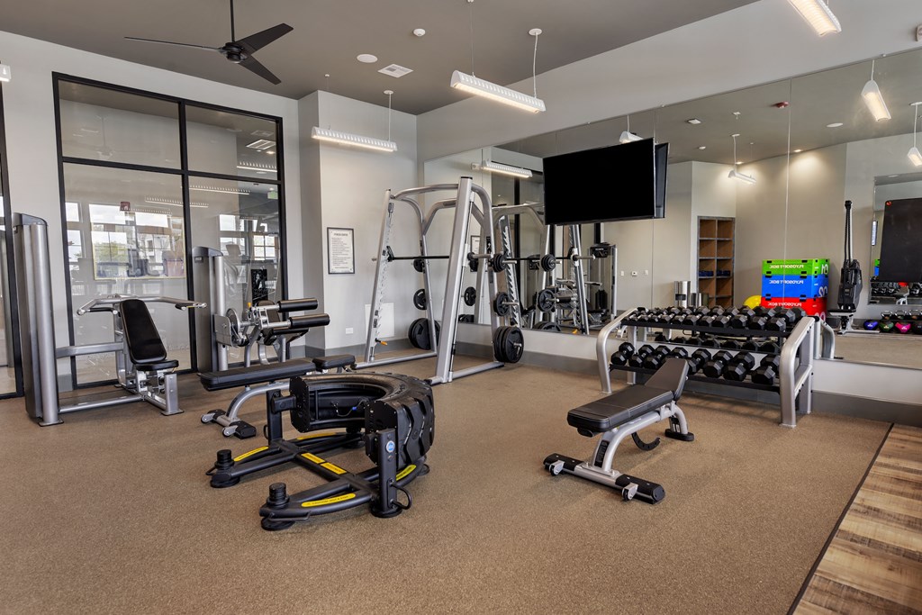 a gym with weights and cardio equipment and a television