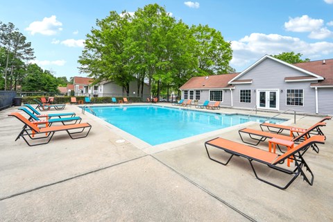 A pool with sun loungers and a house in the background.