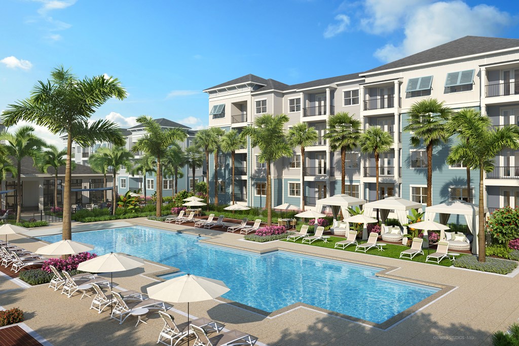 A large swimming pool surrounded by lounge chairs and umbrellas in front of a multi-story apartment building.