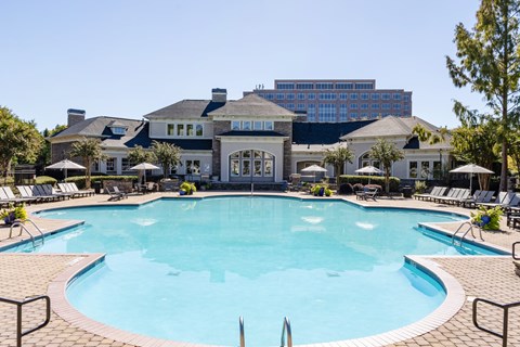 A large swimming pool in front of a building with a blue sky in the background.