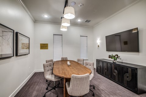 a meeting room with a table and chairs and a tv on the wall