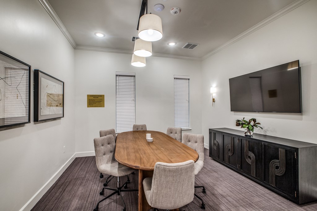 a meeting room with a table and chairs and a tv on the wall