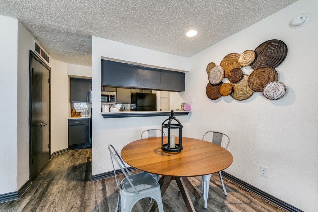 a dining area with a table and chairs and a kitchen in the background