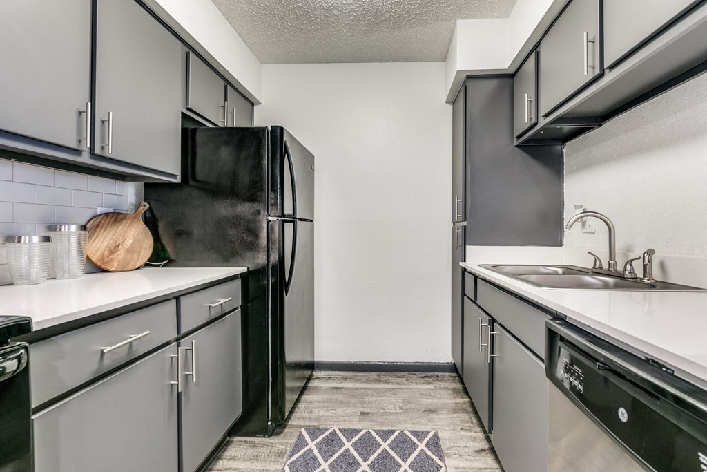 an empty kitchen with white counters and black appliances and a black refrigerator