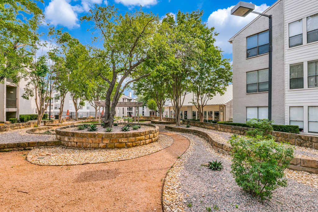 a courtyard between two buildings with trees and plants