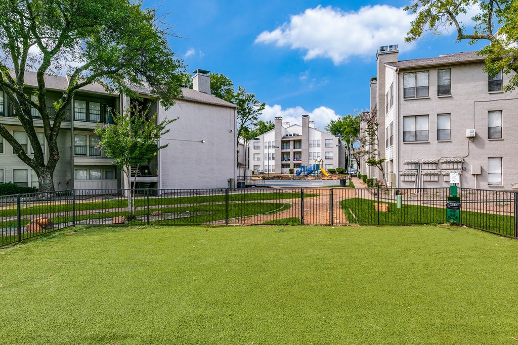 the yard is fenced in with a green lawn and a pool