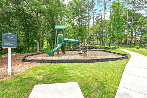 A playground with a green slide and a sign.