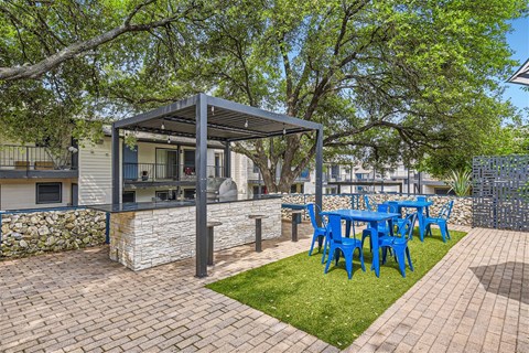 a patio with a blue table and chairs and a grill