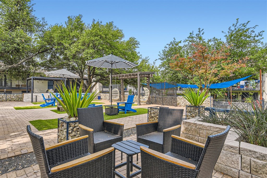 a patio with chairs and umbrellas and a hammock