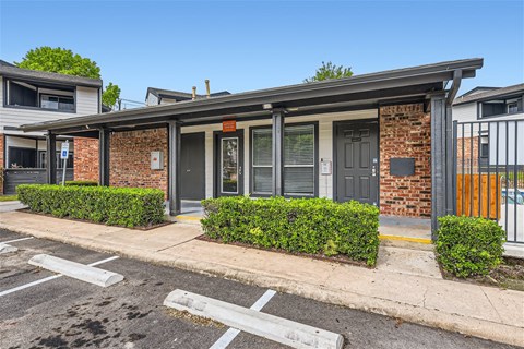 a small brick building with a gray door and a sidewalk
