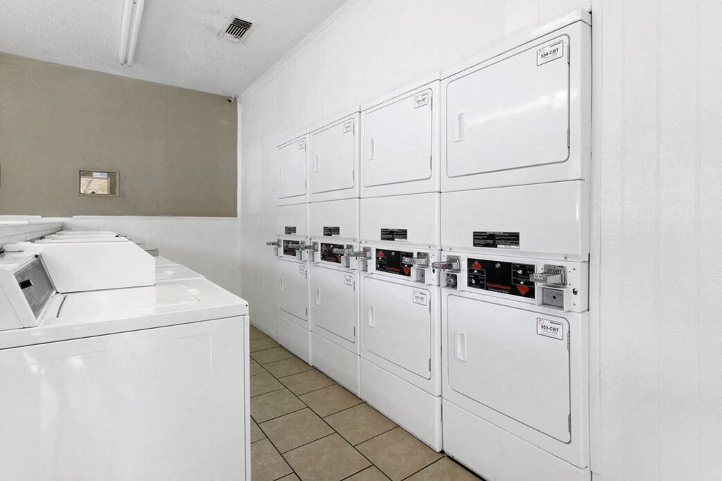 the laundry room is equipped with washer and dryers and a row of white
